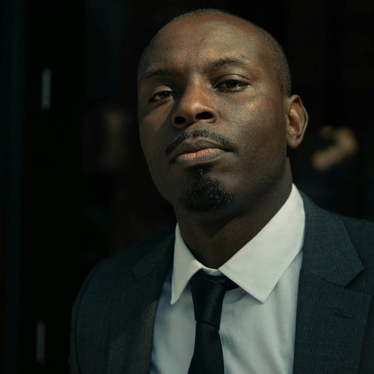 Man in a suit and tie against a dark background