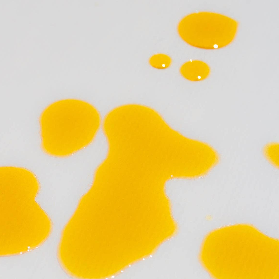 Yellow splatters of serum on a light gray background