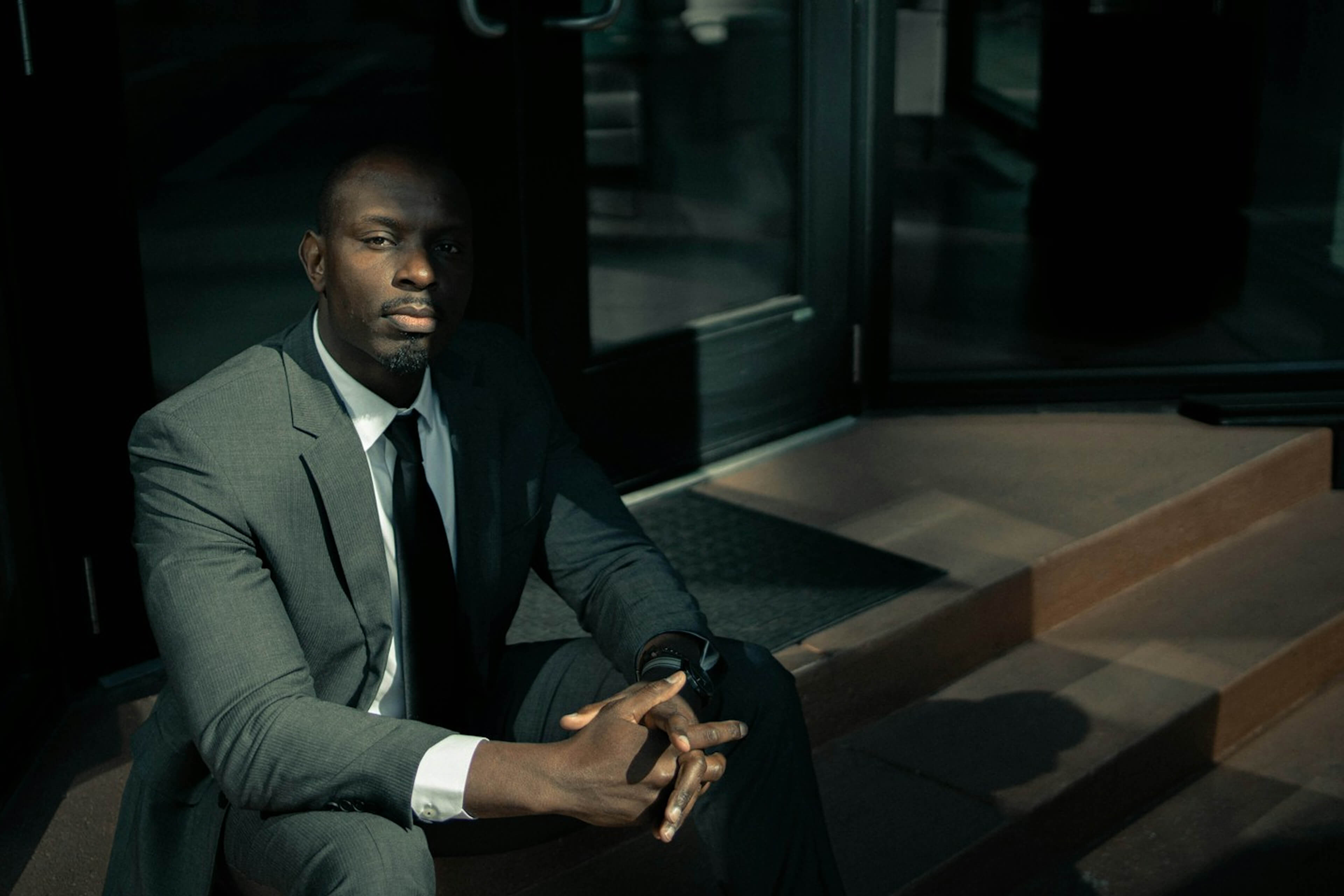 Business man in a suit sitting on steps in a dimly lit room