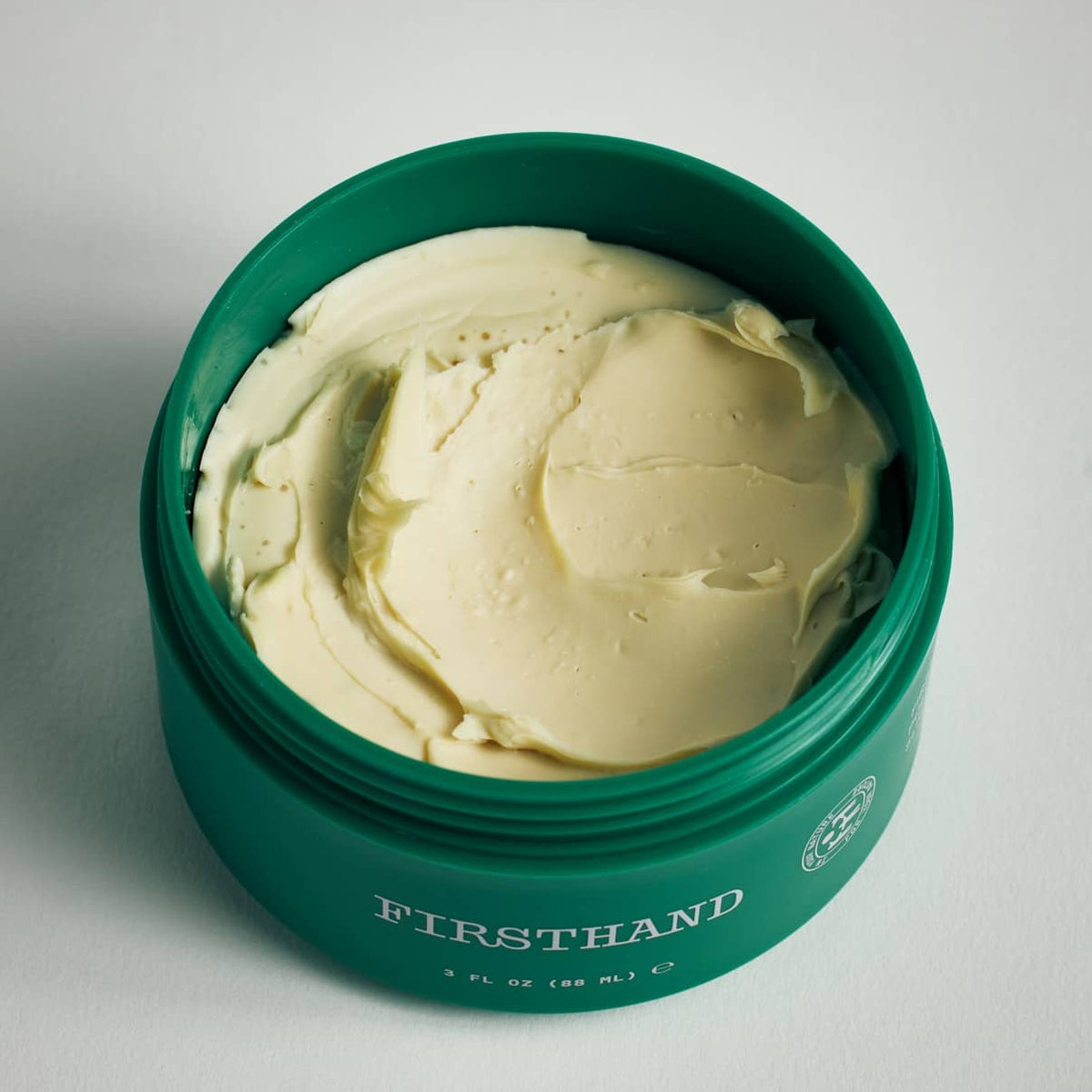 Green container of cream with 'Firsthand Supply' branding on a light gray background