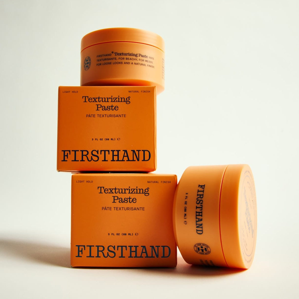 Two jars and a box of Firsthand Texturizing Paste on a light background