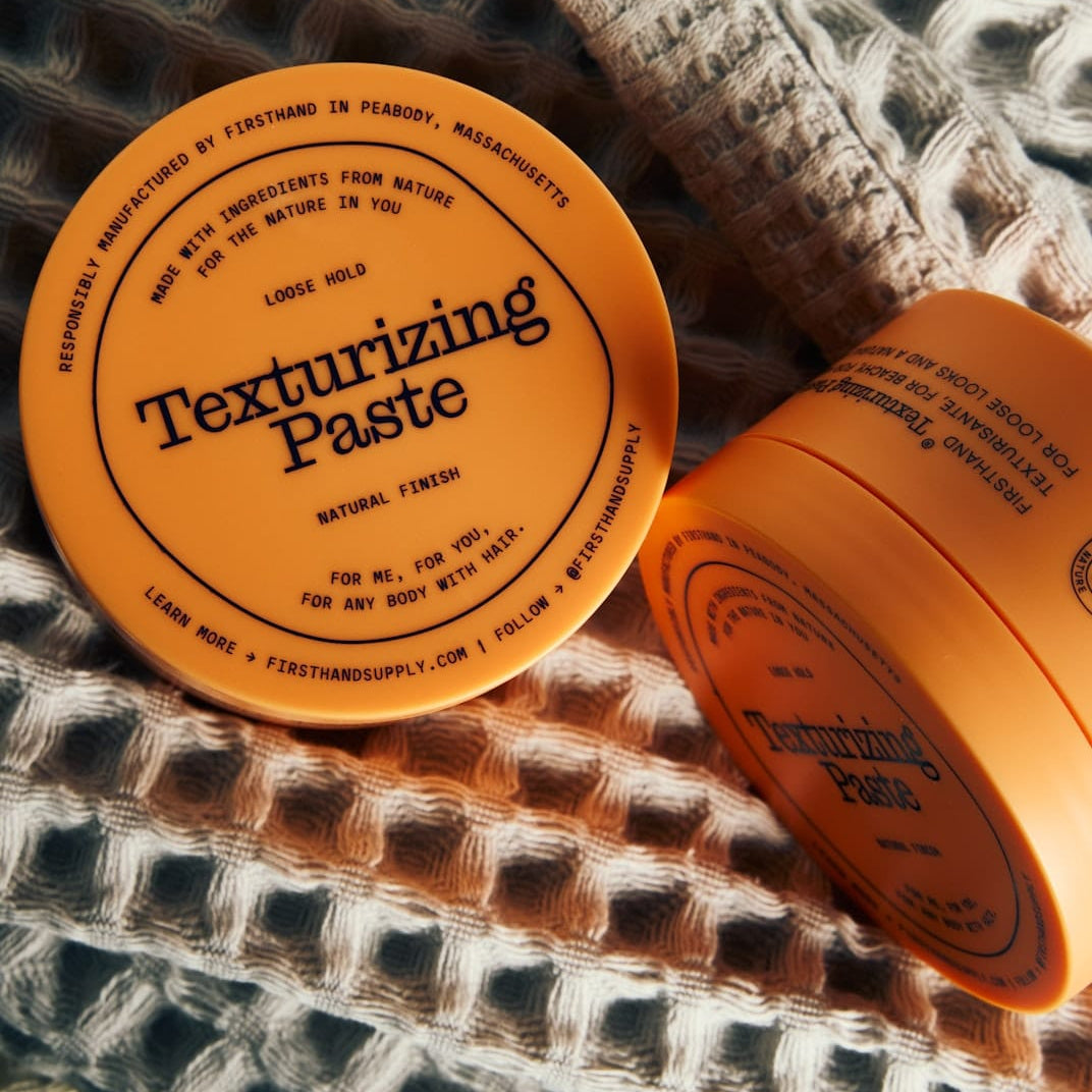 Two containers of Firsthand Supply Texturizing Paste on a textured fabric background